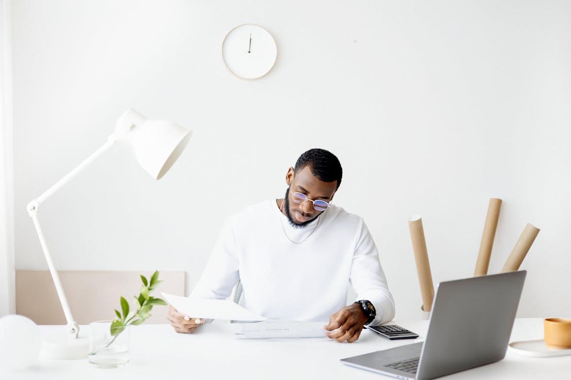 A professional adult working at a minimalist desk with a laptop and papers