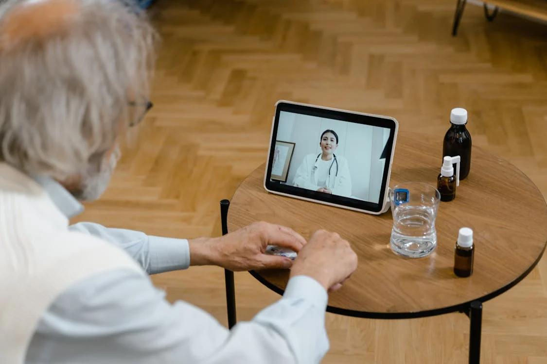 A female doctor visible on a screen during an online consultation with an elderly patient