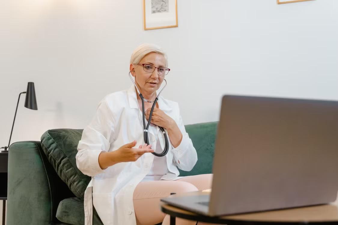 a doctor sitting on a couch and using her laptop.