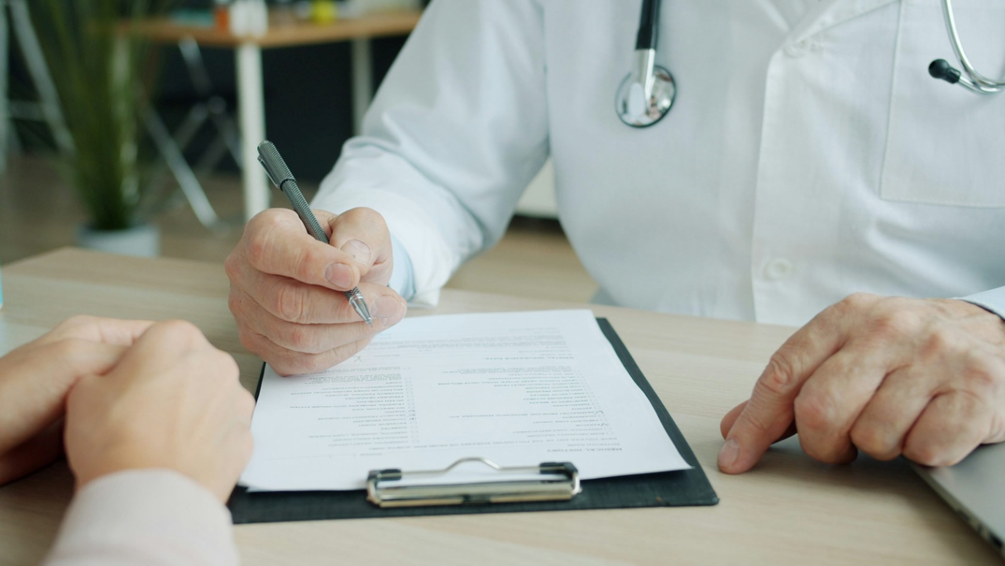 A doctor writing on a clipboard
