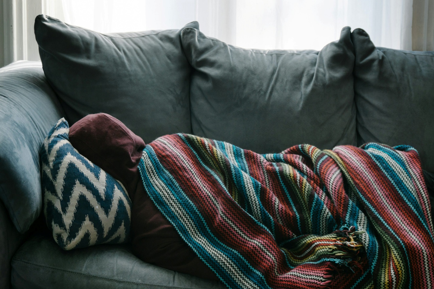 A person sleeping on a gray sofa